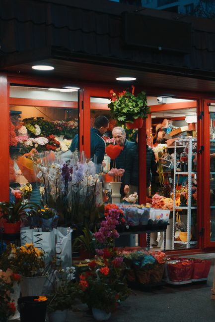 A vibrant floral display outside the flower shop near Tottenham Hale station features a variety of fresh flowers including pink, purple, and yellow blooms arranged in buckets and vases. Potted plants